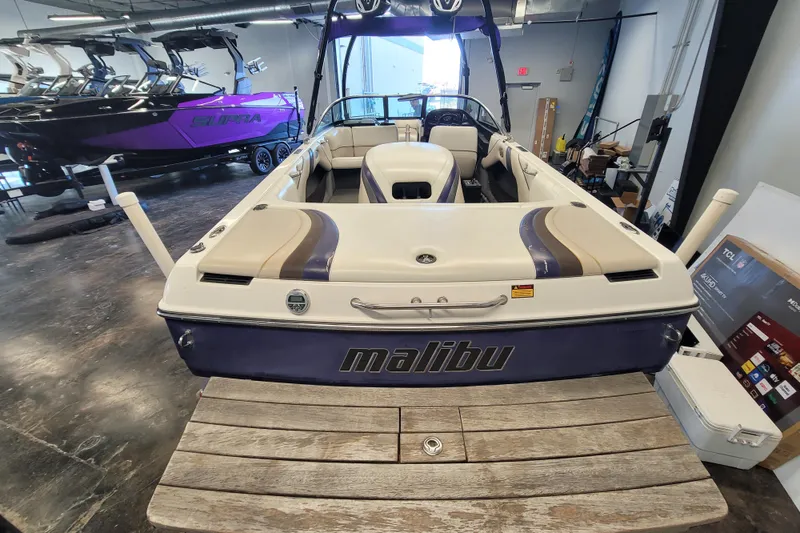 Slide: The Image of 2003 Malibu Sunsetter LXi boat in showroom, rear view with sleek design and seating. - 9