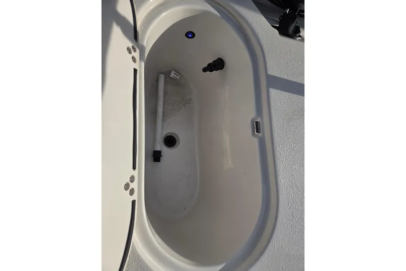 Slide: The Image of Livewell compartment in 2026 Carolina Skiff 178 JLS boat, featuring drain and fittings. - 15