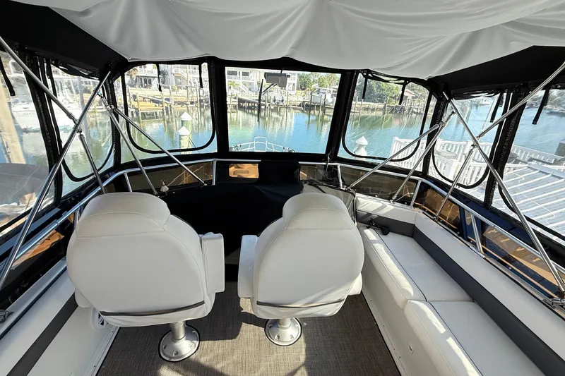 Slide: The Image of Interior view of 1998 Mainship 47 Motor Yacht with white seating and panoramic windows. - 11
