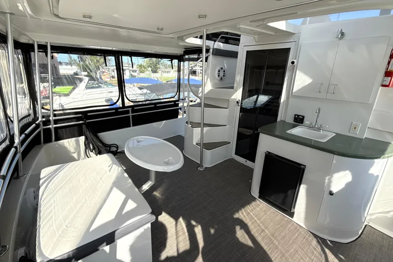 Slide: The Image of 1998 Mainship 47 Motor Yacht interior with seating, table, kitchenette, and spiral staircase. - 26