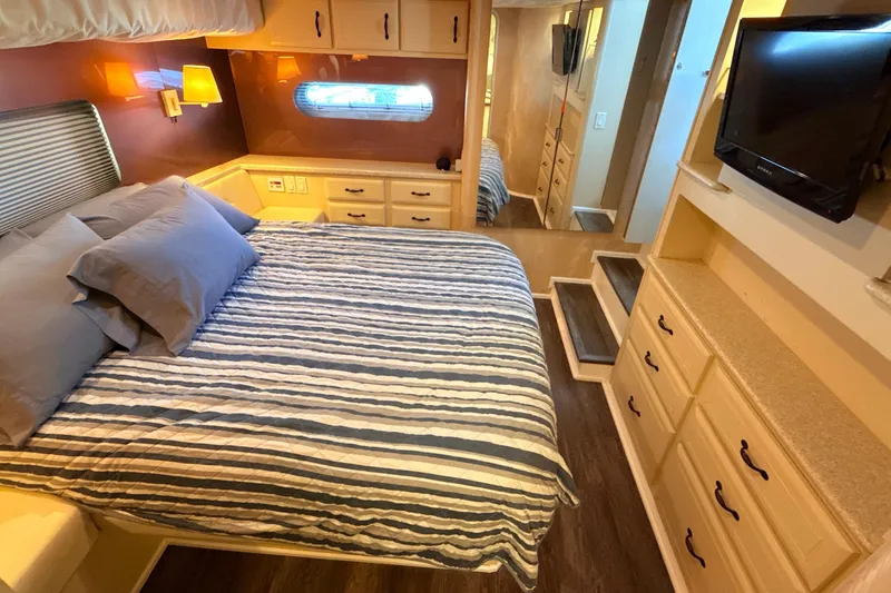 Slide: The Image of Luxurious bedroom interior of 1998 Mainship 47 Motor Yacht with striped bedding and ample storage. - 42