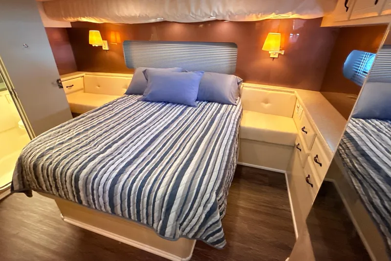 Slide: The Image of Cozy bedroom in 1998 Mainship 47 Motor Yacht with striped bedding and warm lighting. - 45