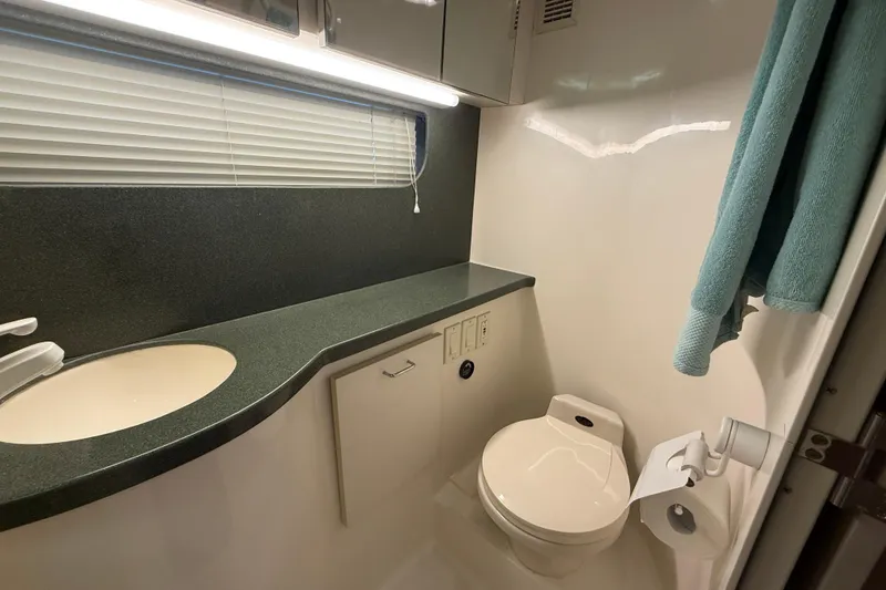 Slide: The Image of Bathroom interior of 1998 Mainship 47 Motor Yacht with sink, toilet, and teal towel. - 52