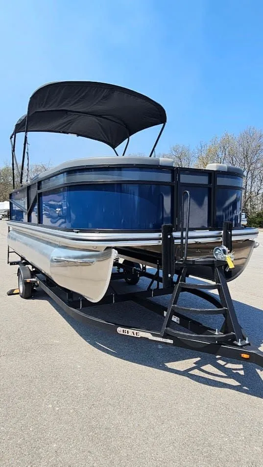 Slide: The Image of 2025 Lowe LS 190 pontoon boat with black canopy on trailer. - 7