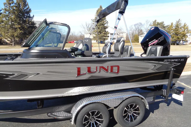 Slide: The Image of 2026 Lund 2075 Impact XS boat on trailer, featuring sleek design and modern seating. - 13