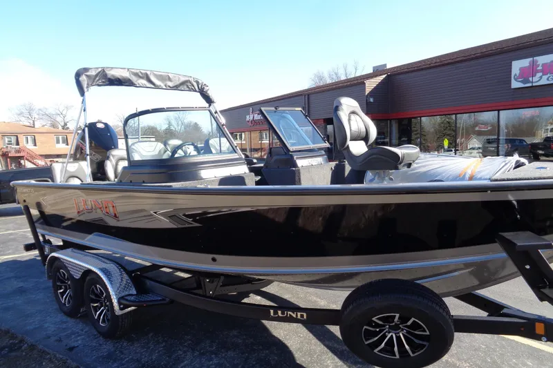Slide: The Image of 2026 Lund 2075 Impact XS boat on trailer, parked outside a dealership. - 16