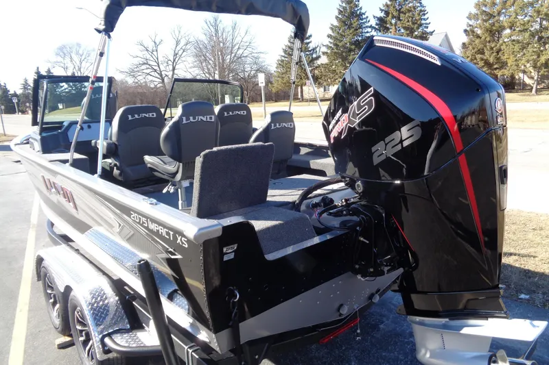 Slide: The Image of 2026 Lund 2075 Impact XS boat with powerful 225 engine, parked outdoors. - 2