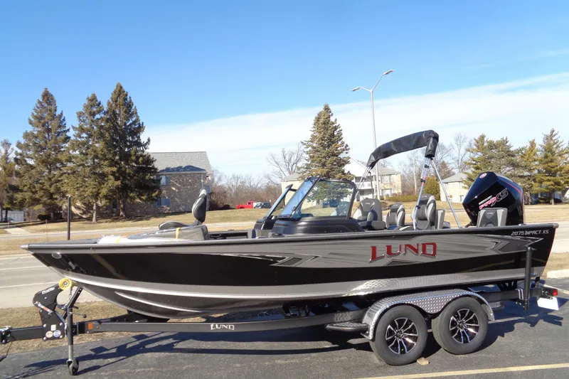 Slide: The Image of 2026 Lund 2075 Impact XS boat on trailer, parked outdoors under clear blue sky. - 3