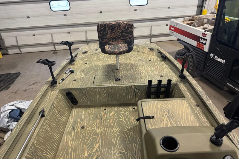 Slide: The Image of 2019 Tracker Grizzly 1754 MVX SC boat with camo seating and rod holders in a garage. - 8