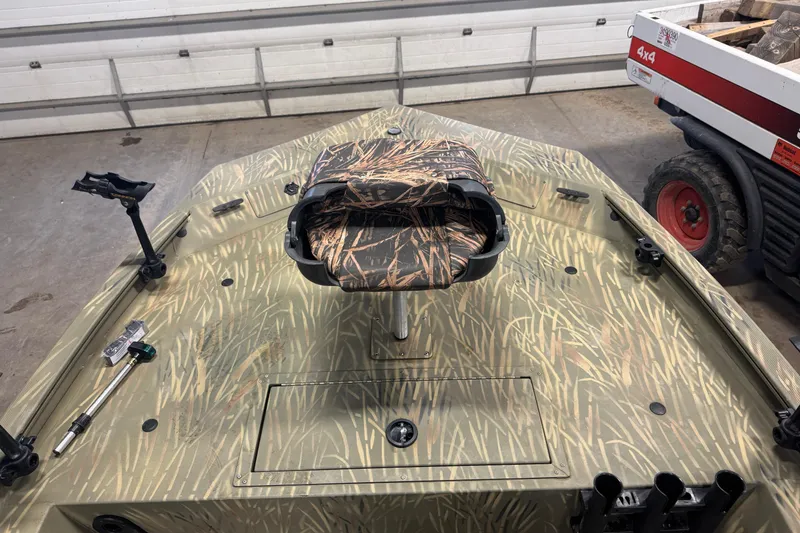 Slide: The Image of 2019 Tracker Grizzly 1754 MVX SC boat with camo pattern in a garage setting. - 9