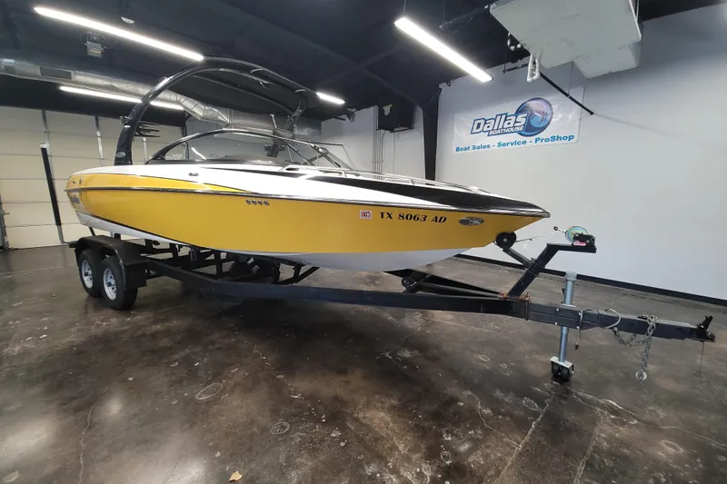 The Image of 2006 Malibu Wakesetter 23 LSV boat in showroom, yellow hull, on trailer. - 1
