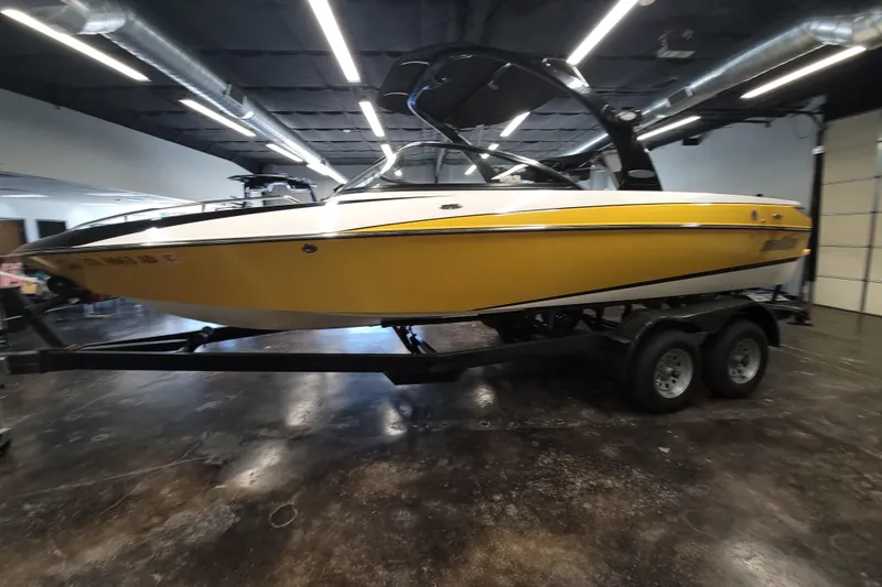 Slide: The Image of 2006 Malibu Wakesetter 23 LSV boat in a showroom, yellow exterior, on a trailer. - 5