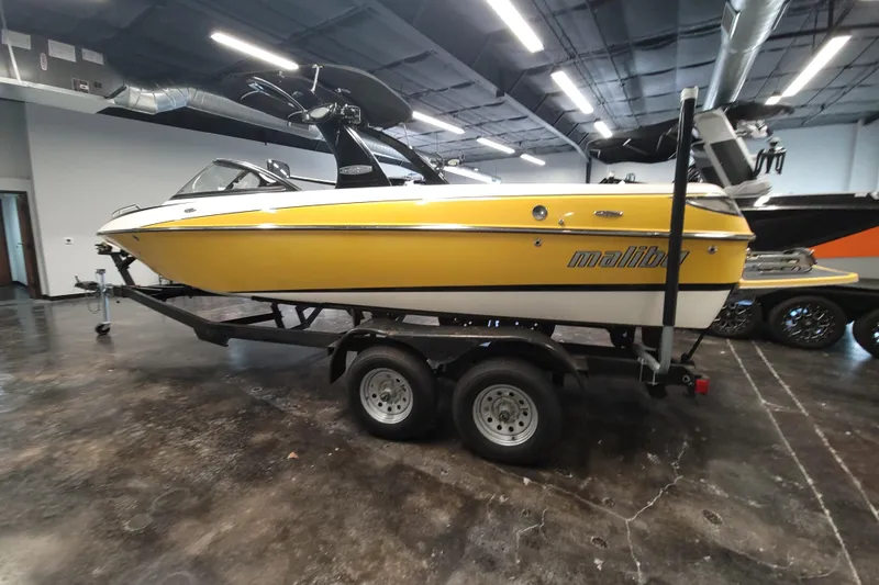 Slide: The Image of 2006 Malibu Wakesetter 23 LSV boat in a showroom, yellow and white exterior. - 6