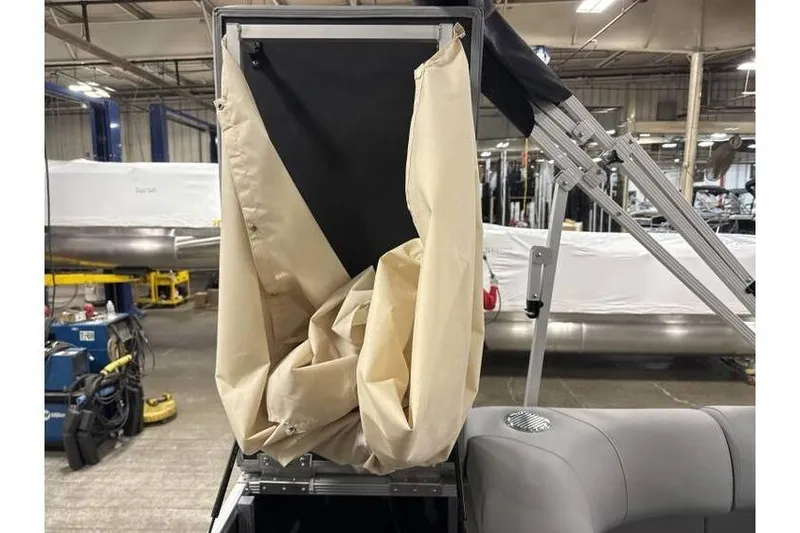 Slide: The Image of 2026 Bennington 21 SL boat with privacy changing curtain in a warehouse setting. - 16