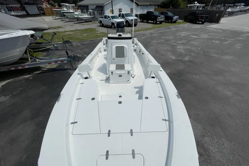 Slide: The Image of 2023 BlackJack 256 Bay boat, white deck, parked outdoors with trailers and vehicles nearby. - 14