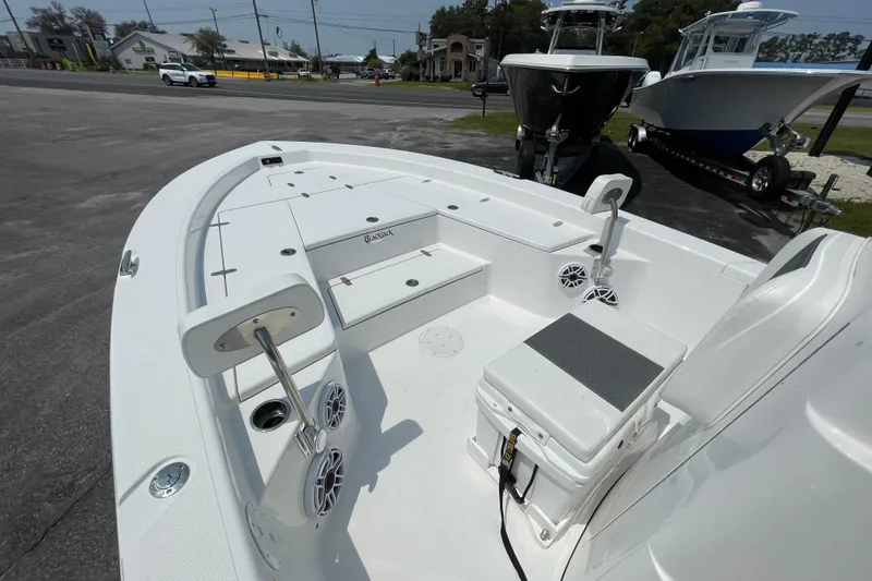 Slide: The Image of 2023 BlackJack 256 Bay boat interior with seating and storage, parked outdoors. - 15