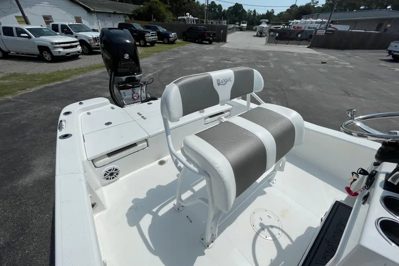 Slide: The Image of 2023 BlackJack 256 Bay boat interior with seating and motor, parked outdoors. - 8