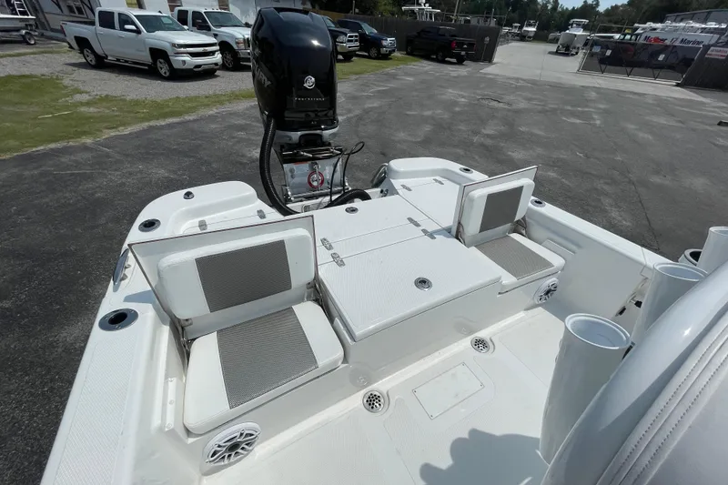 Slide: The Image of 2023 BlackJack 256 Bay boat interior with seating and motor, parked outdoors. - 9
