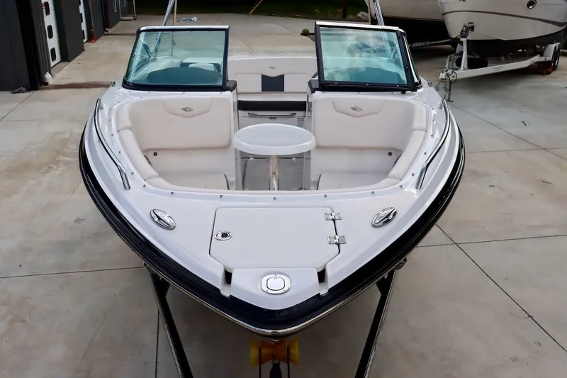 Slide: The Image of 2017 Chaparral 227 SSX boat with open bow seating and table, parked on concrete. - 27