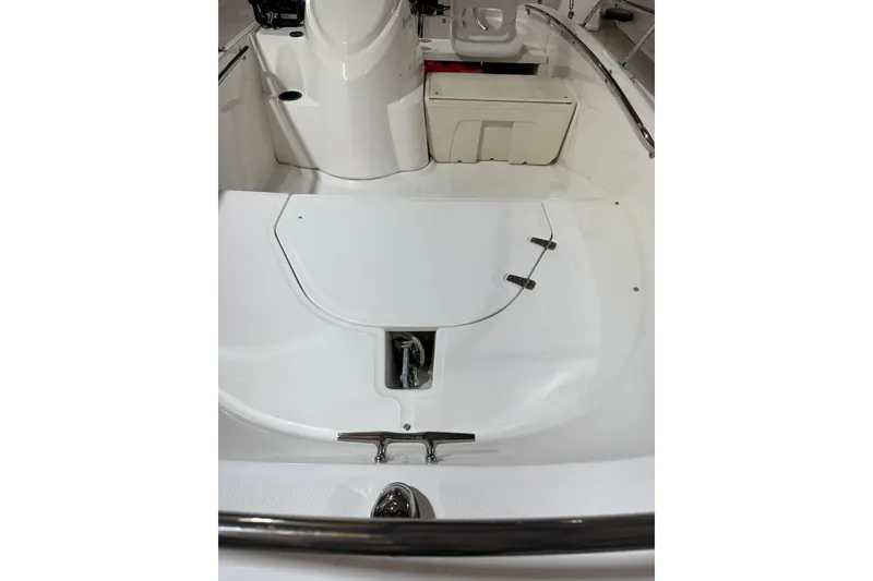 Slide: The Image of 2015 Boston Whaler 150 Super Sport boat interior, featuring white seating and storage area. - 10