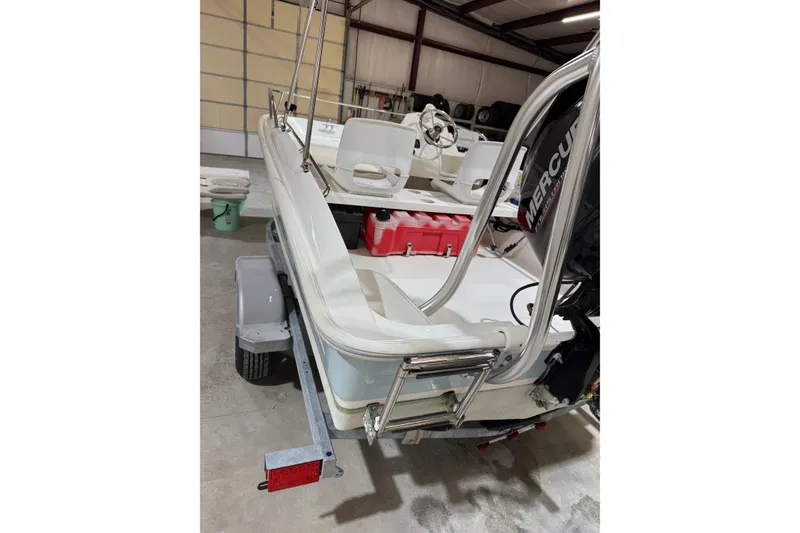 Slide: The Image of 2015 Boston Whaler 150 Super Sport boat in garage, featuring Mercury engine. - 7