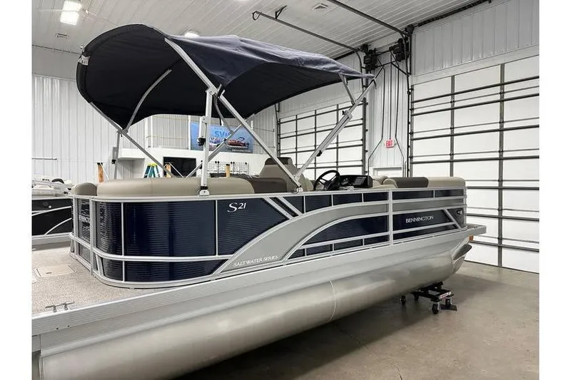 Slide: The Image of 2026 Bennington 21 SSR Quad Bench pontoon boat in showroom, blue and beige design. - 10