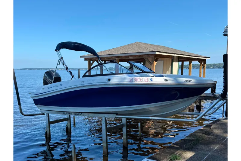The Image of 2017 Tahoe 550 TS boat on lift by lake, under clear blue sky. - 1