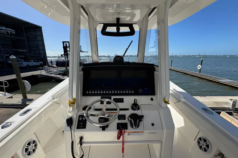 Slide: The Image of 2023 Regulator 31 boat cockpit with steering wheel and control panel, docked by the water. - 14