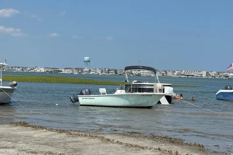 Slide: The Image of 2016 Sportsman Island Reef 17 Center Console boat anchored near shore, with coastal town backdrop. - 11