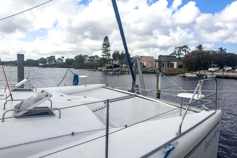 Slide: The Image of Catamaran Leopard 42, 2002 model, docked by a scenic waterfront with cloudy skies. - 2
