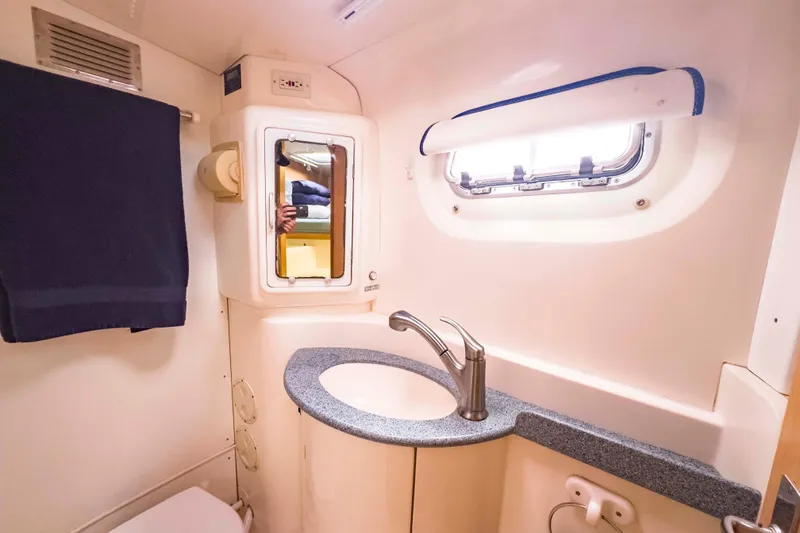 Slide: The Image of Compact bathroom in a 2002 Leopard 42 yacht, featuring a sink, mirror, and window. - 42