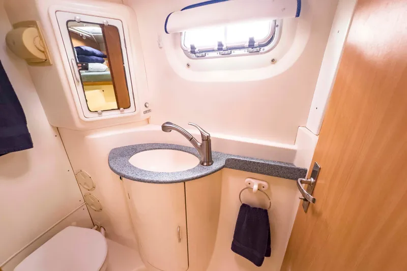 Slide: The Image of Compact bathroom in a 2002 Leopard 42 yacht, featuring sink, mirror, and porthole window. - 43