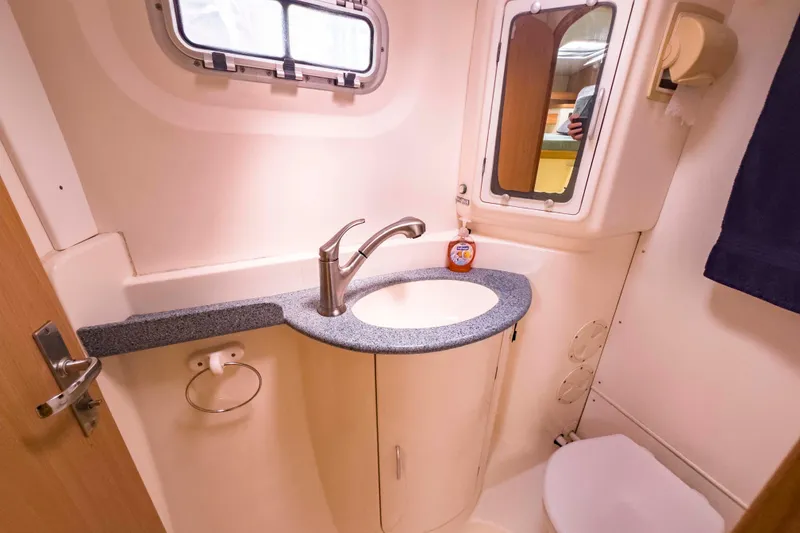 Slide: The Image of Compact bathroom in a 2002 Leopard 42 yacht with sink, mirror, and porthole window. - 49