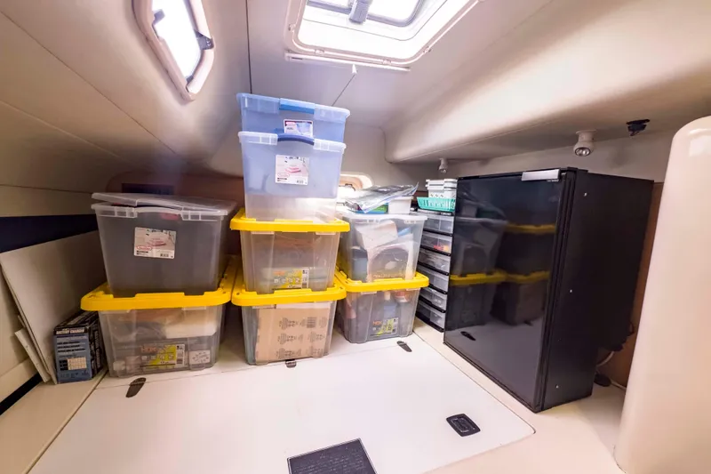 Slide: The Image of Storage area in a 2002 Leopard 42 yacht with organized plastic bins and a compact fridge. - 61
