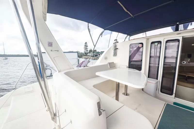 Slide: The Image of Spacious deck of 2002 Leopard 42 catamaran with seating and table, docked by the water. - 7