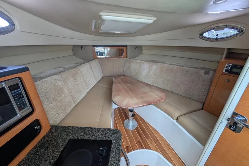 Slide: The Image of 2010 Robalo R305 Walkaround cabin interior with seating, table, and kitchenette. - 12