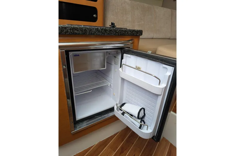 Slide: The Image of Compact refrigerator inside 2010 Robalo R305 Walkaround boat, featuring wooden cabinetry and granite countertop. - 17