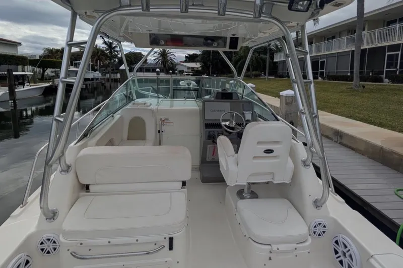 Slide: The Image of 2010 Robalo R305 Walkaround boat interior with helm and seating, docked by waterfront. - 4