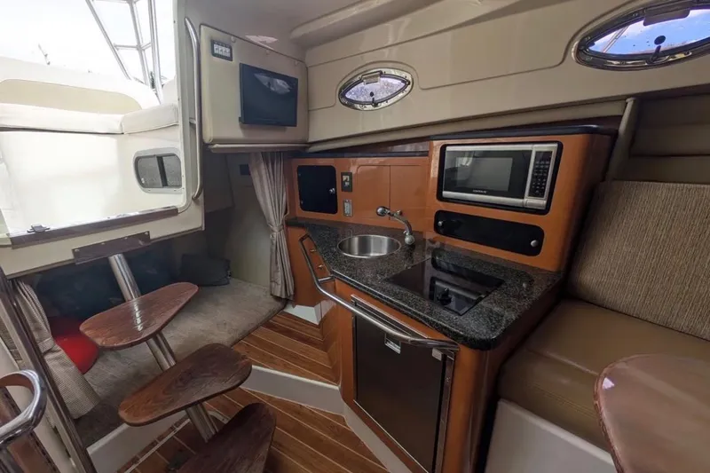 Slide: The Image of 2010 Robalo R305 Walkaround cabin interior with kitchenette, microwave, and seating area. - 9