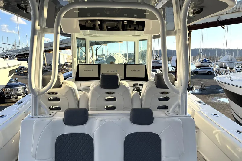 Slide: The Image of 2019 HCB 39 Speciale boat interior with Garmin displays, white seating, and marina background. - 12