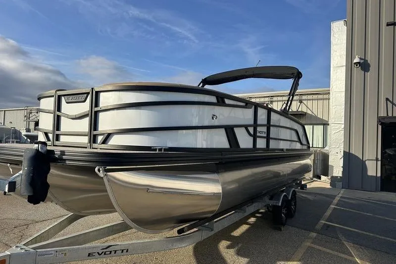 The Image of 2026 Evotti 523CS pontoon boat on trailer outside industrial building. - 1