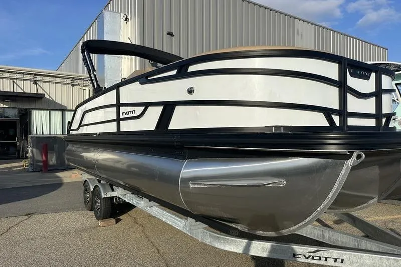 Slide: The Image of 2026 Evotti 523CS pontoon boat on trailer, parked outside industrial building. - 4