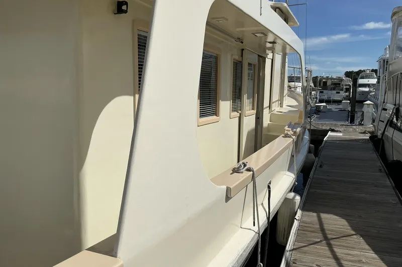 Slide: The Image of 2009 Hugh Huff Custom Pilothouse Trawler docked at marina under clear blue sky. - 14