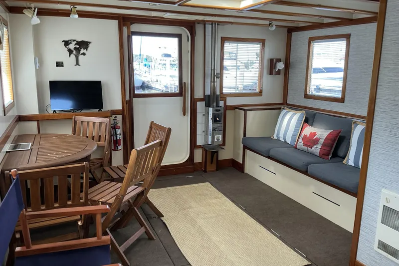 Slide: The Image of Interior of 2009 Hugh Huff Custom Pilothouse Trawler with cozy seating and wooden dining area. - 16