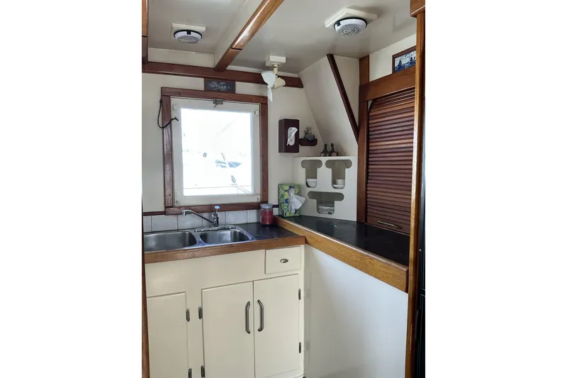 Slide: The Image of 2009 Hugh Huff Custom Pilothouse Trawler kitchen with sink, window, and wooden cabinetry. - 22