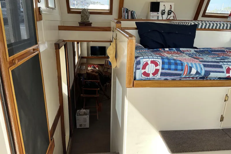 Slide: The Image of Interior of 2009 Hugh Huff Custom Pilothouse Trawler with nautical-themed bedding and cozy seating area. - 32
