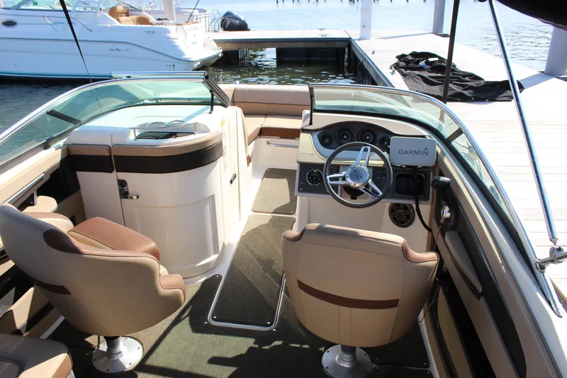 Slide: The Image of 2016 Sea Ray SunDeck 220 interior with steering wheel and seating, docked by the water. - 21