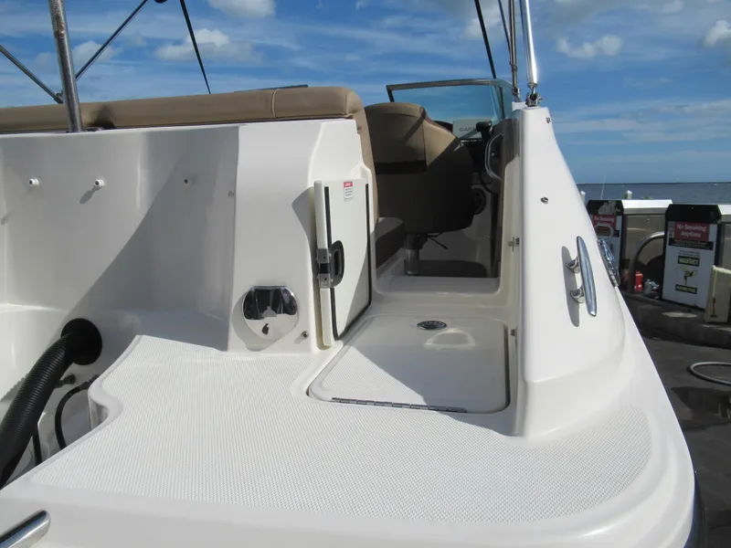 Slide: The Image of 2016 Sea Ray SunDeck 220 boat interior with seating and controls, under a clear blue sky. - 5