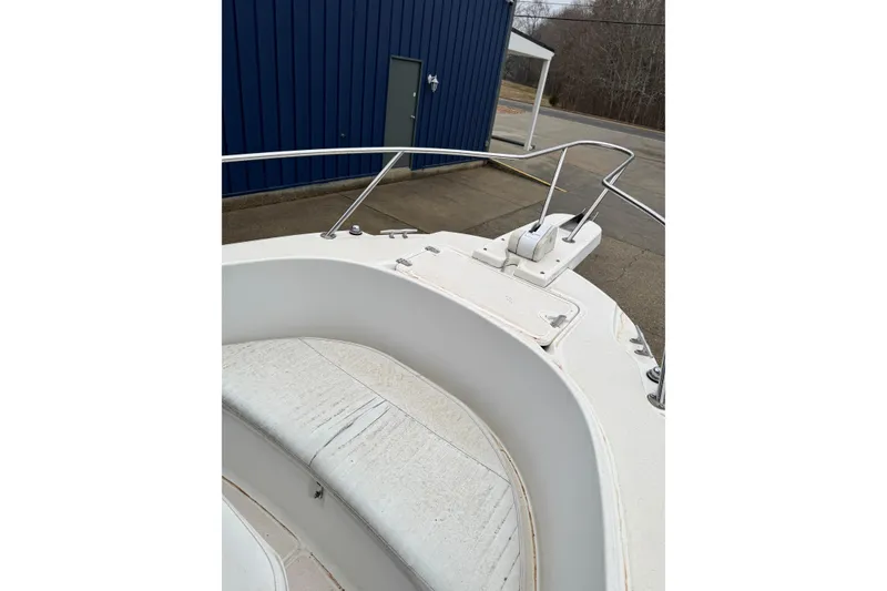 Slide: The Image of 1999 Boston Whaler 21 Outrage boat bow with seating and railing, docked near blue building. - 10