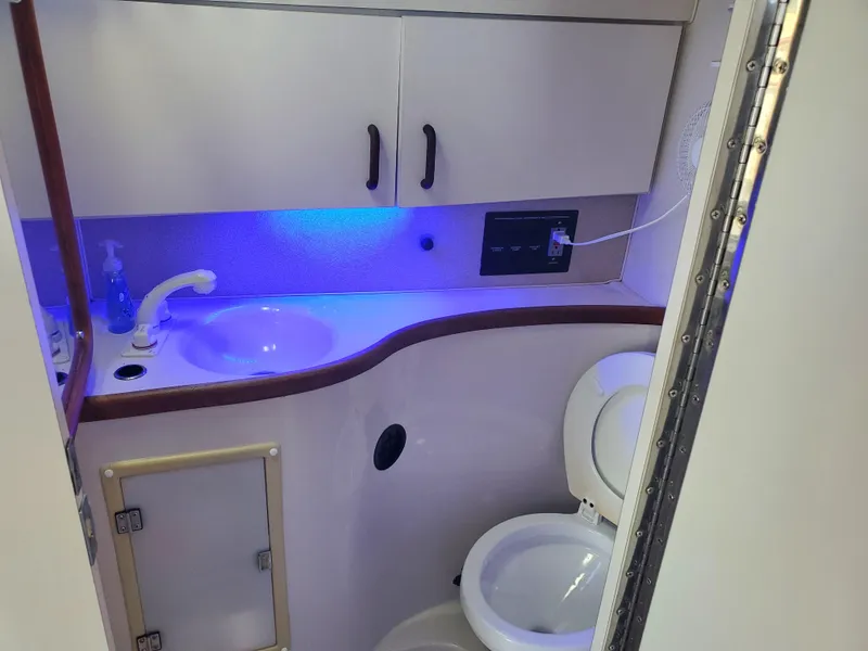 Slide: The Image of 1991 Wellcraft 3300 Sport Bridge bathroom with sink, toilet, and blue accent lighting. - 10